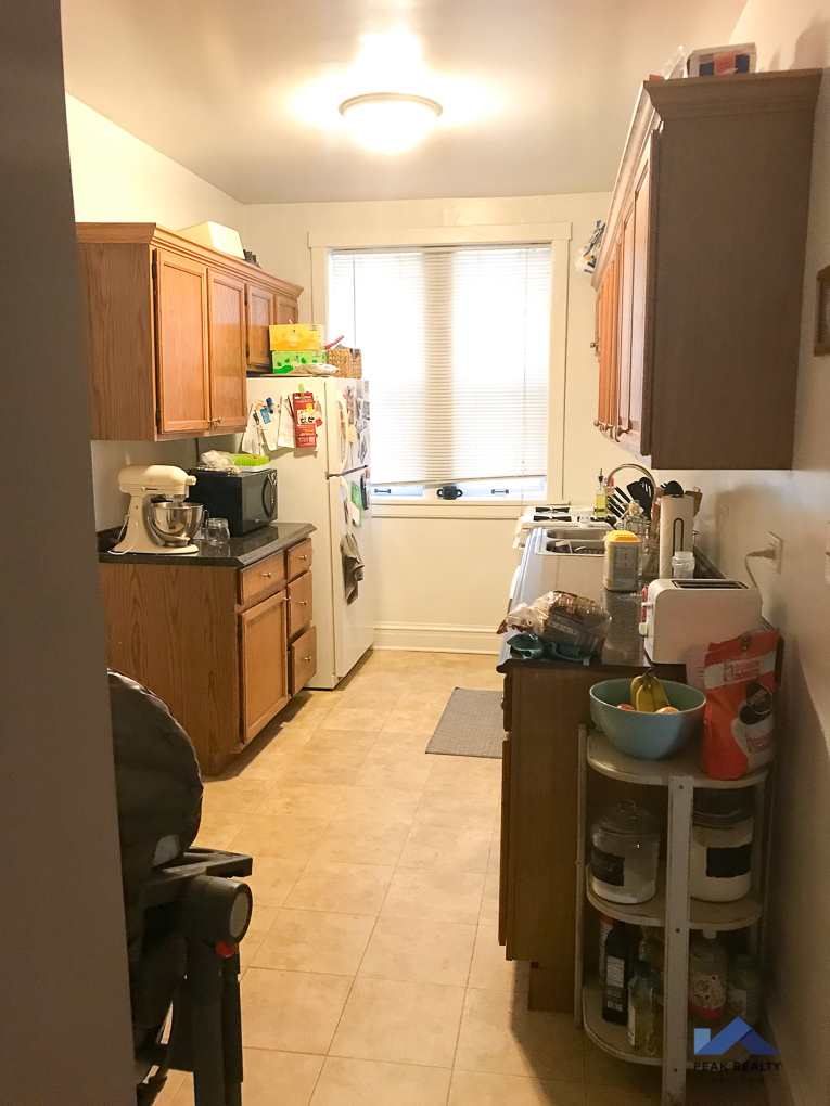 a small kitchen with wooden cabinets and a white refrigerator